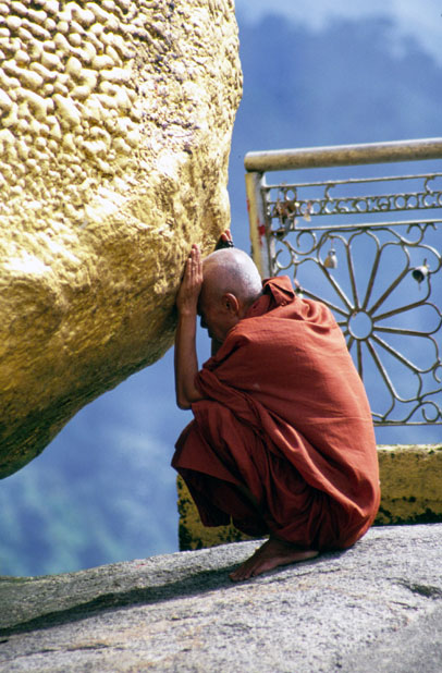 Monk prayes at holy stupa at Kyaiktiyo. Myanmar (Burma).
