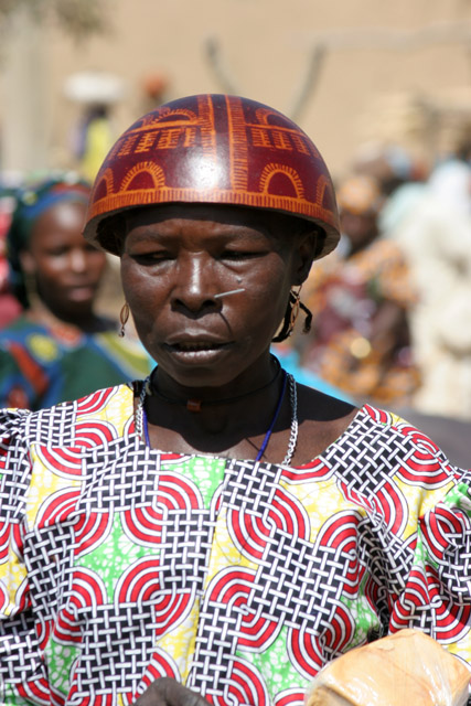 Woman at Tourou village at Mandara Mountains. Local fashion is red wooden calabashes on women' heads. They look rather like army helmets and which indicate things like their marital status. Cameroon.