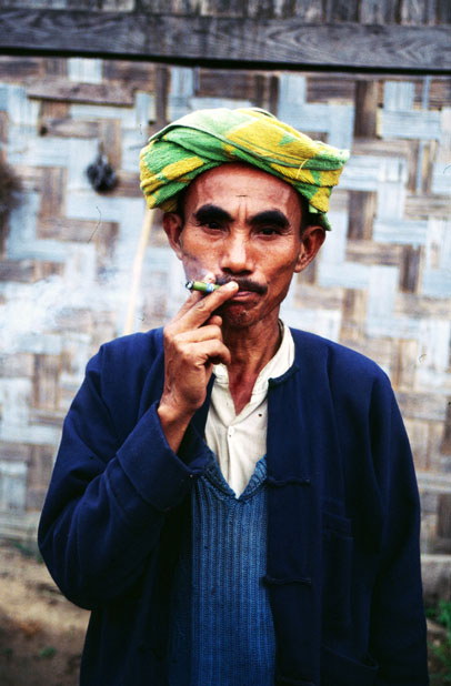 Local man (from hill tribe) is smoking traditional burma cigar called cheroot. Area around Kalaw village. Myanmar (Burma).
