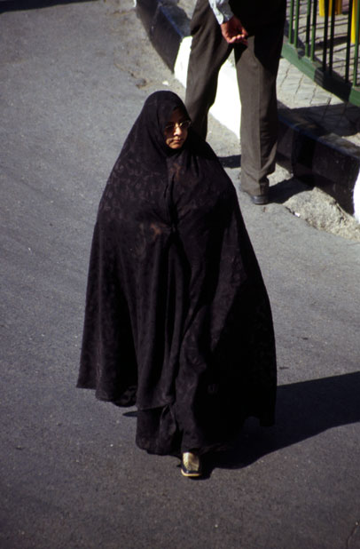 Traditional color of woman dress is black in Iran. Woman is dressed in black chador. Mashhad. Iran.