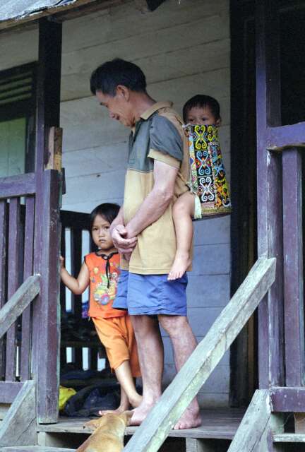 Dayak man is carrying baby in Sungai Barang village. Kalimantan,  Indonesia.